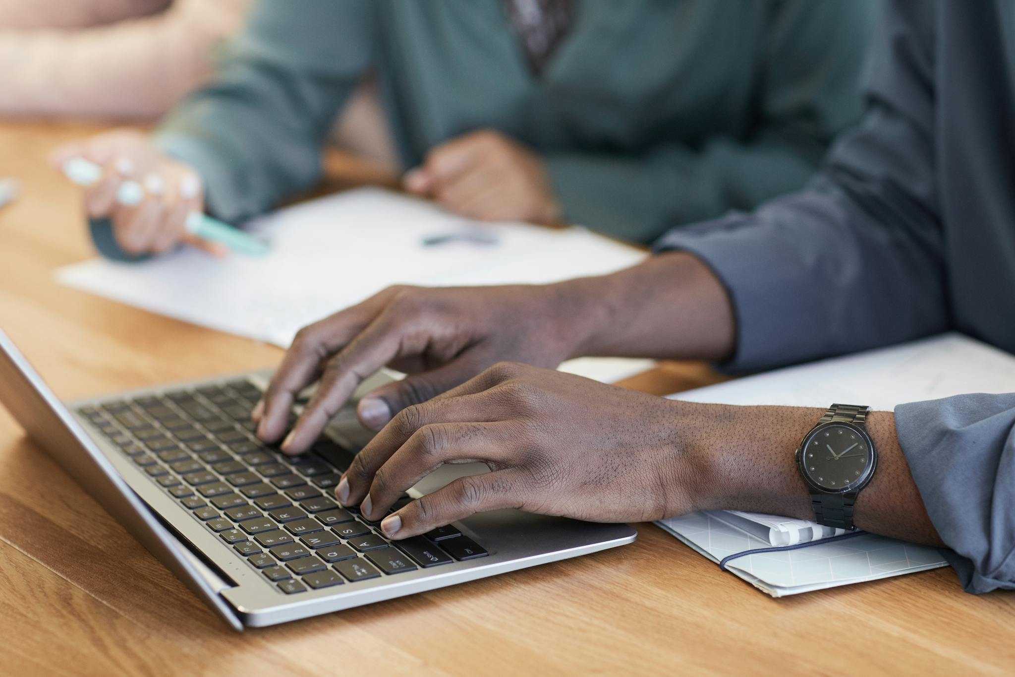 Close-up of hands typing on a laptop, with a focus on modern office tools and teamwork.